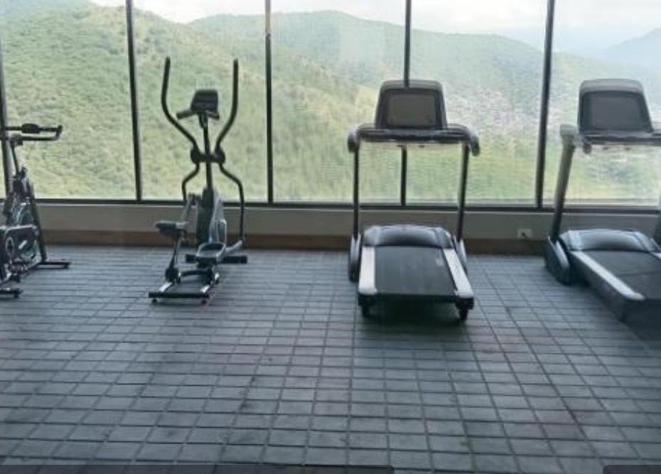 Gimnasio del edificio con máquinas y ventanal hacia la montaña