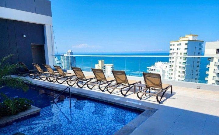 Piscina del edificio con asoleadoras y vista al mar Caribe